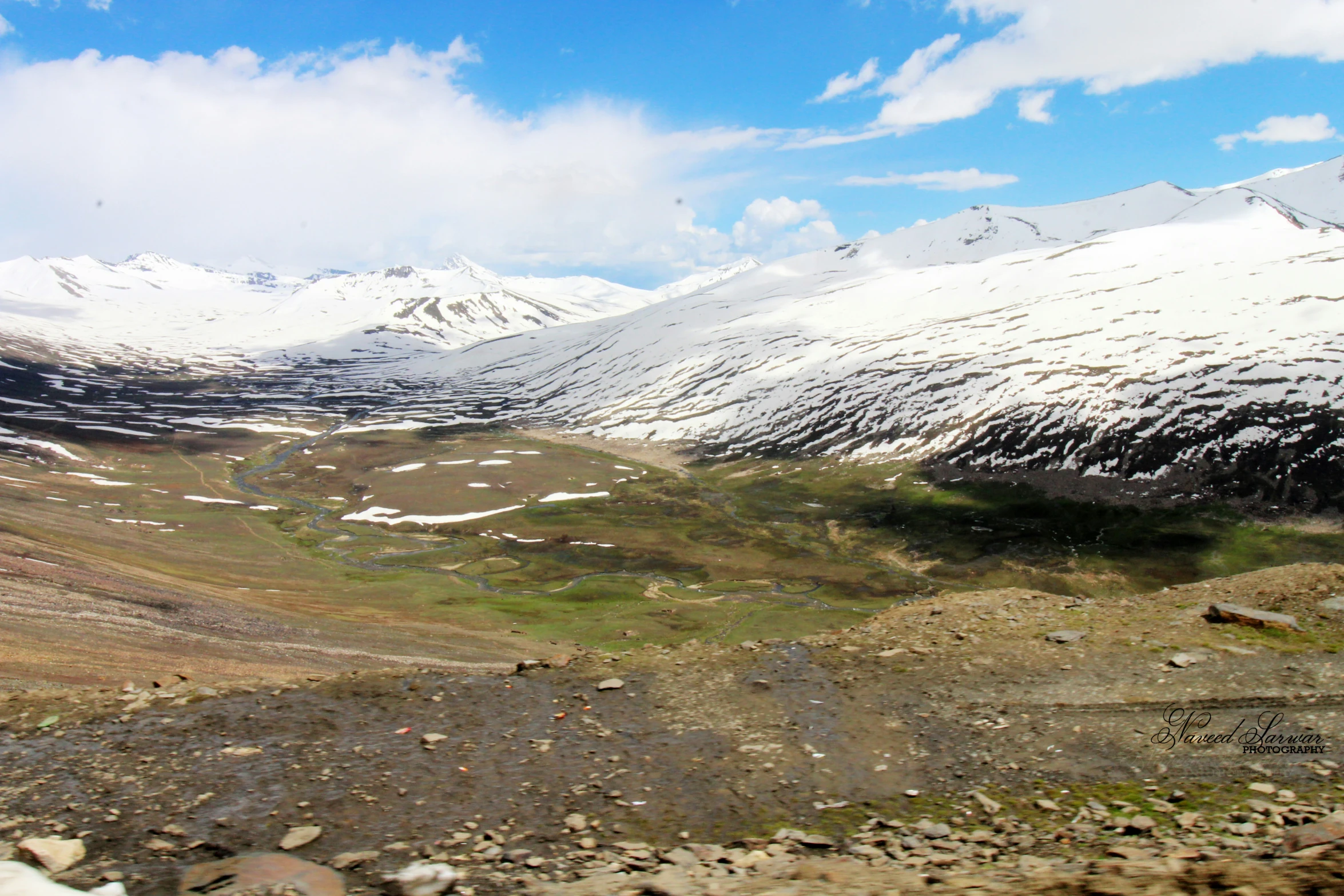 a snow covered mountains with small green meadows and fields