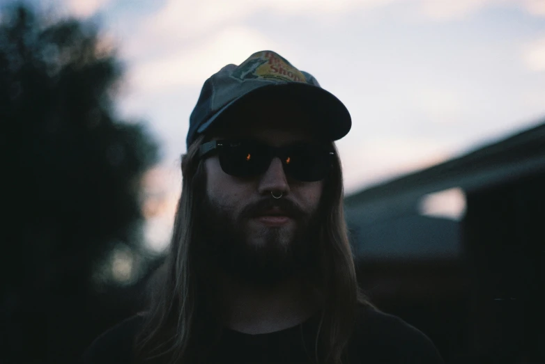 a man with sunglasses and hat next to a wall