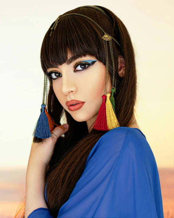 a woman with long dark hair wearing earrings and a blue top