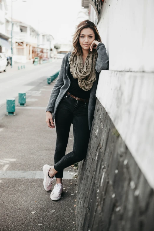 a woman leaning on a wall while talking on her cell phone