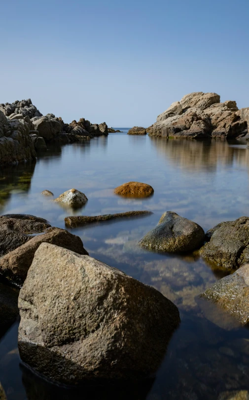 rocks in the water and a person on a cell phone
