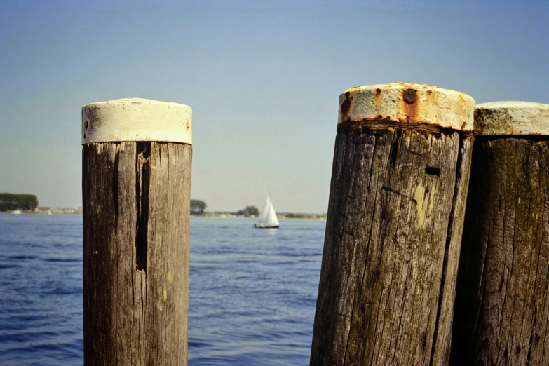 two wooden posts with one sticking out to sea