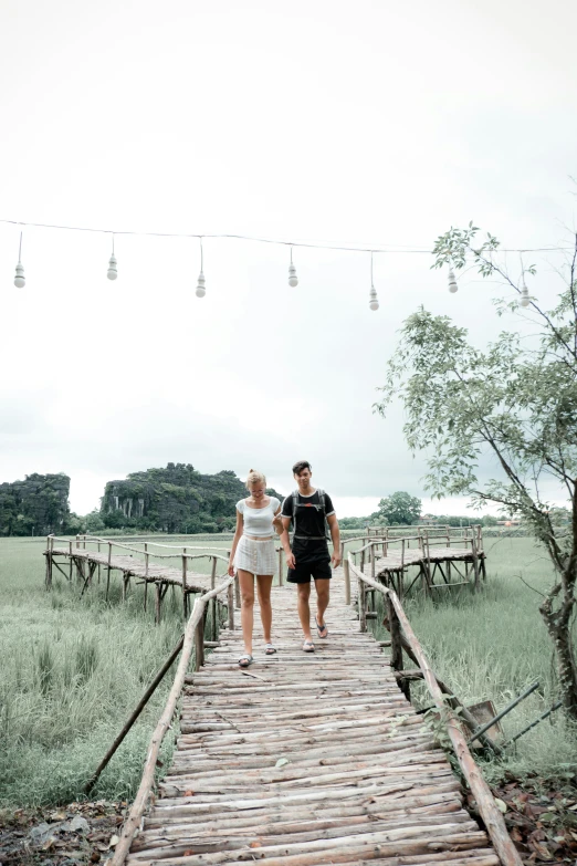 two people walking across a wooden bridge