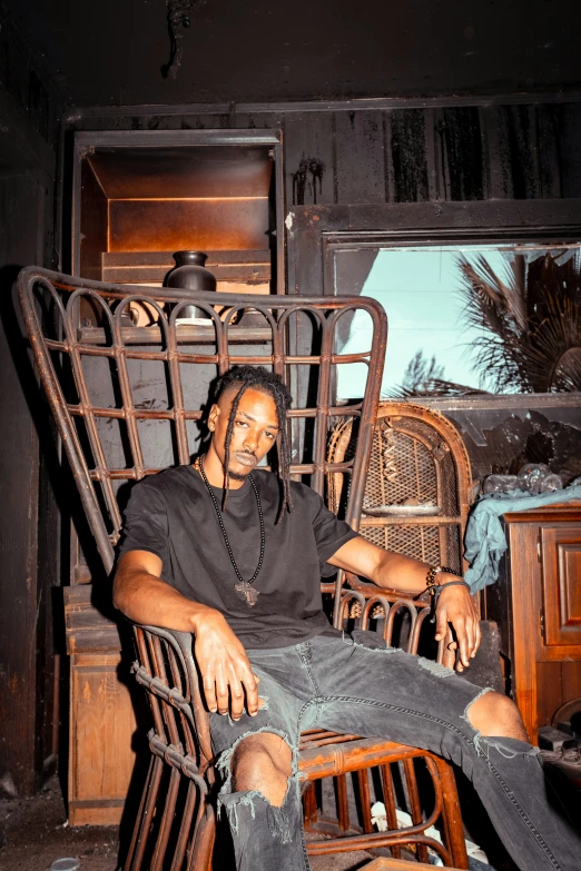 a man in a dark shirt is seated on an ornate chair