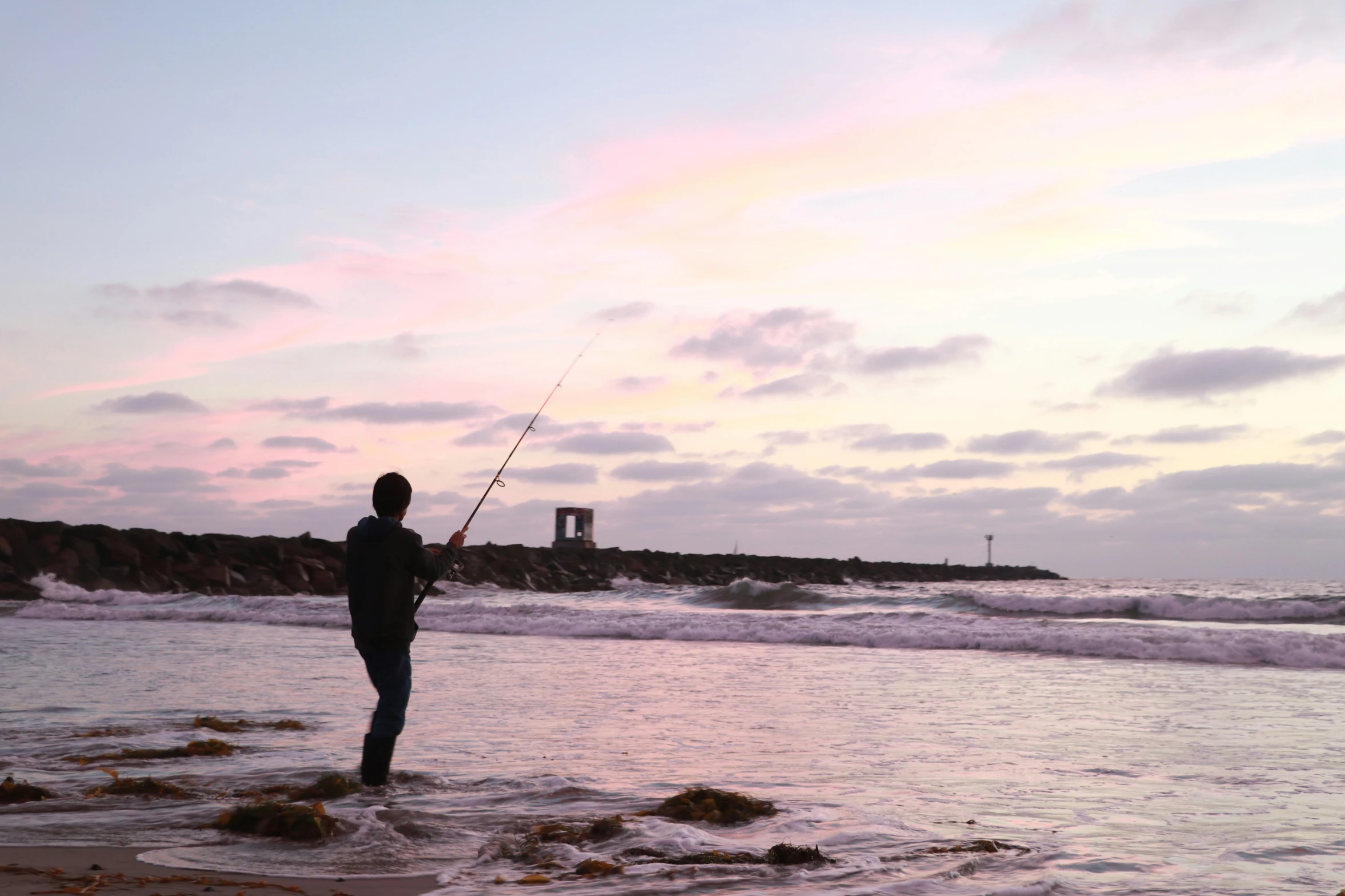 man standing at the edge of the beach near ocean