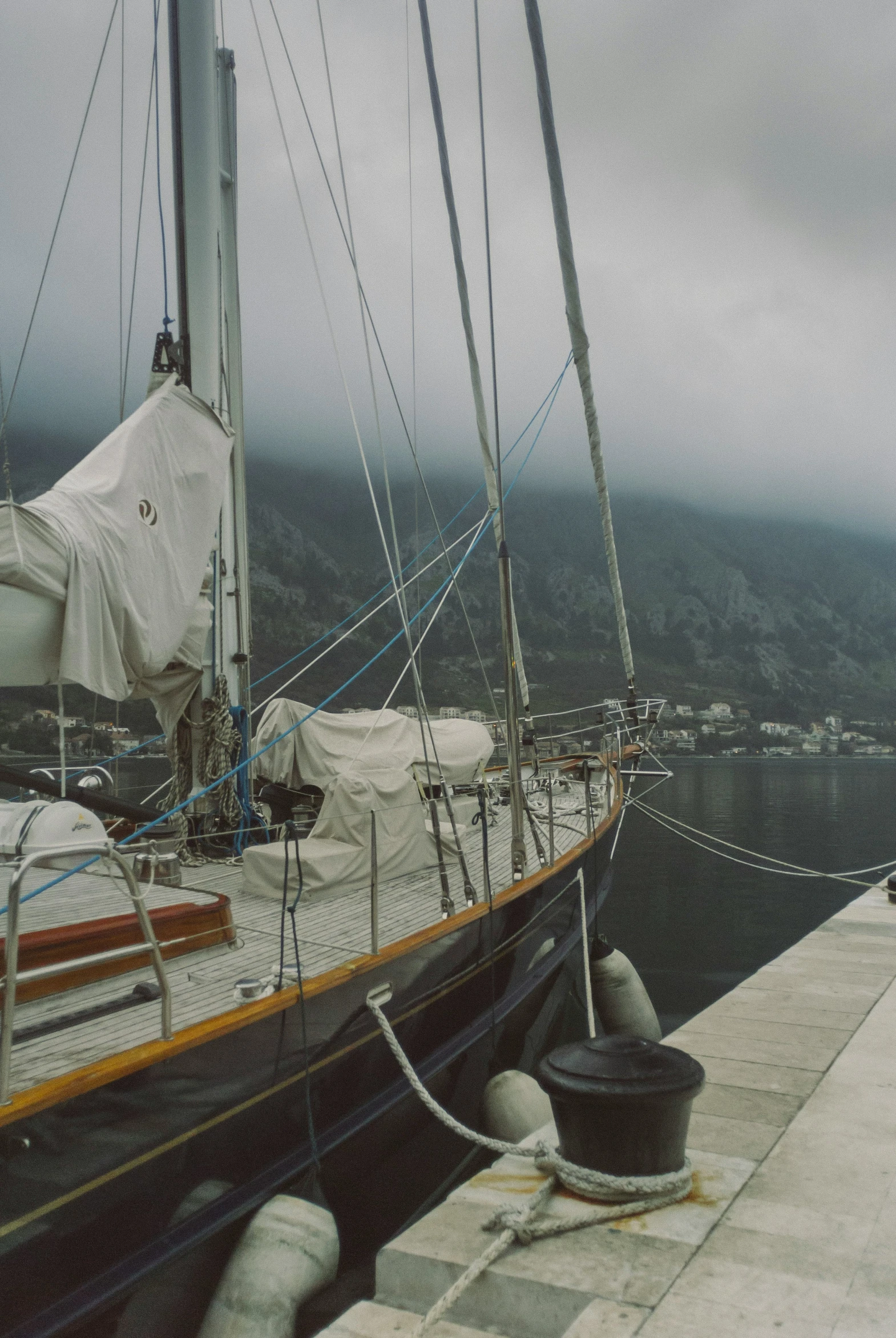 sailboats are tied up near a dock on a dark day