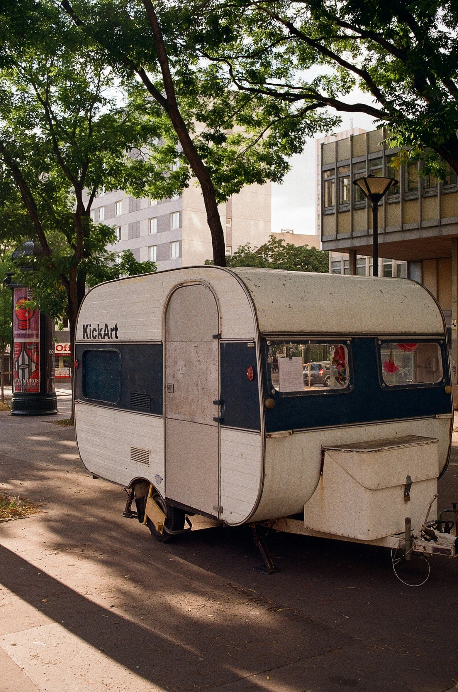 an old trailer parked near some trees and buildings