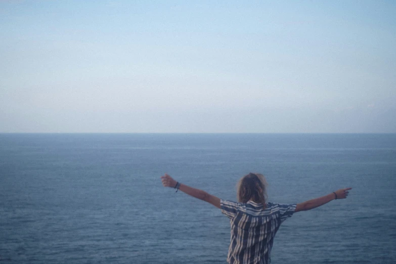 the back view of a person in front of the ocean and the sky