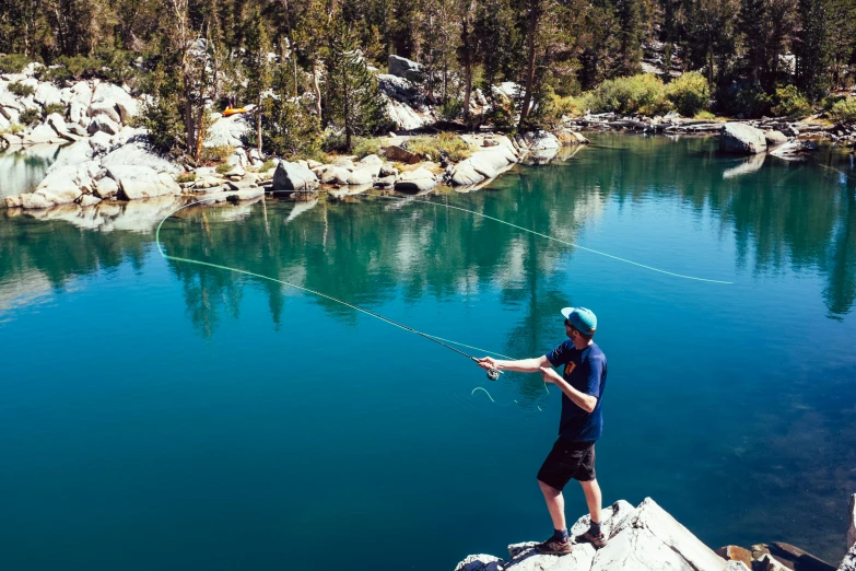 a person on rocks by water holding a fishing rod