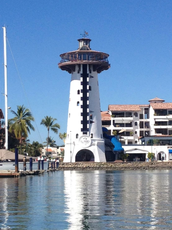 a light house on the shore with a large building next to it