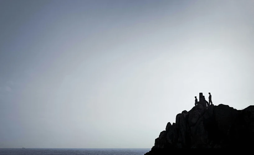 a group of people sitting on top of a rock formation on top of the ocean