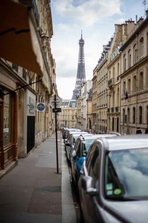 cars are parked along the street next to the eiffel tower