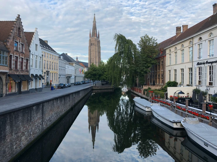 a narrow waterway is lined with older buildings and a church tower