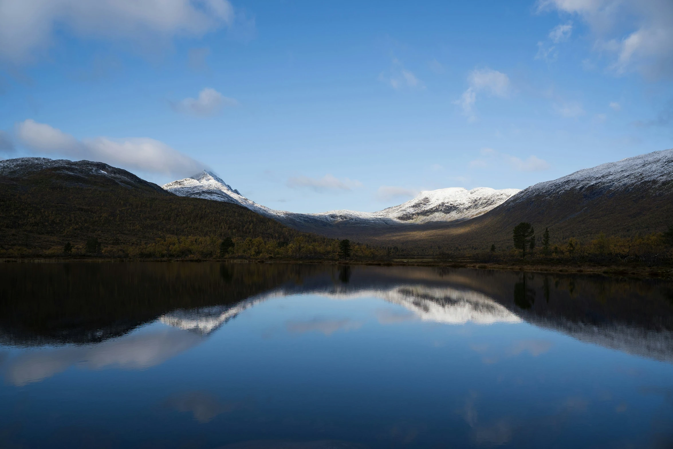 snow covered mountains are around a calm river