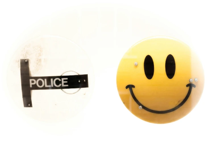 a smiley face and a police sign with holes in the wall