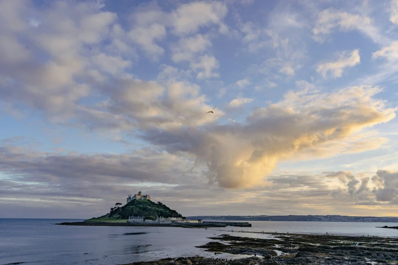 a small island in the ocean under a cloudy sky