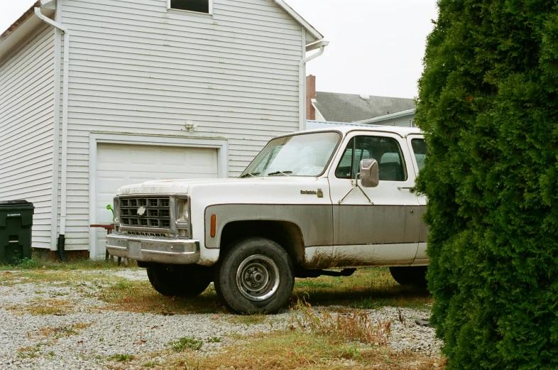 an old white truck parked in front of a house