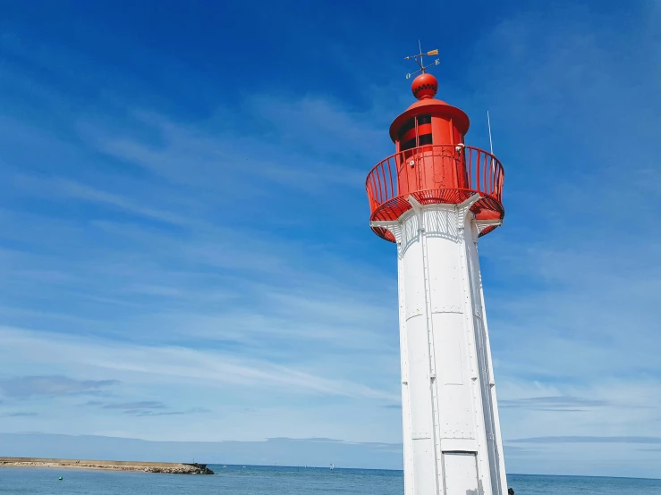 a red and white lighthouse on the shore of the ocean