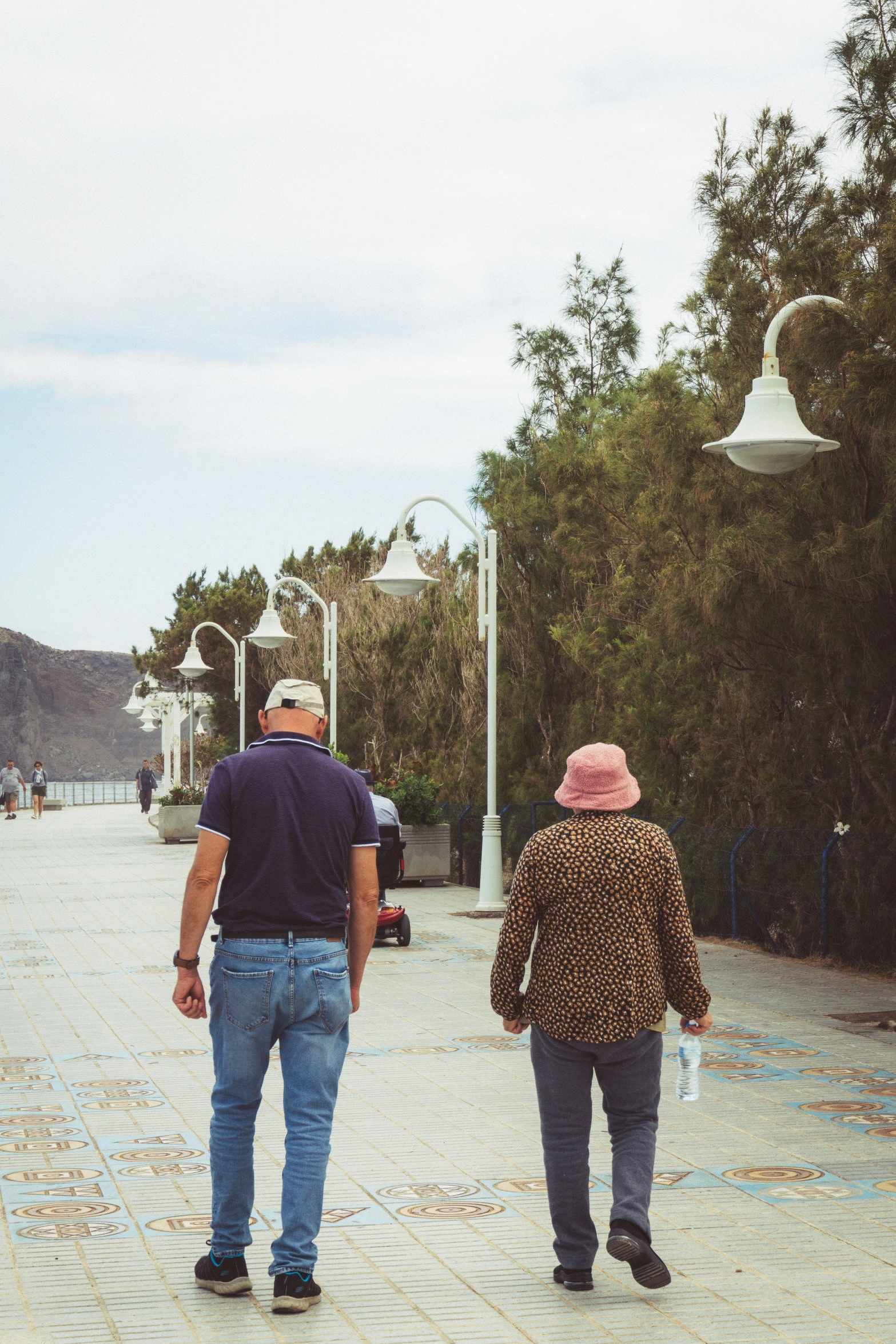 man and woman walking on paved area in front of trees