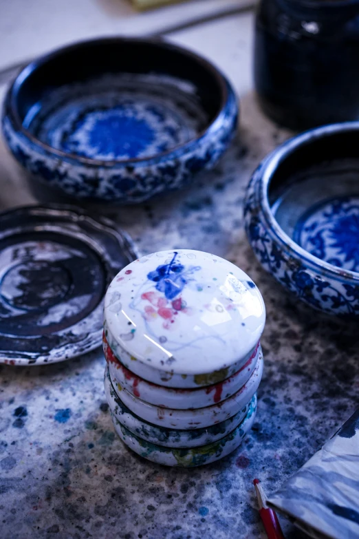 several plates sitting on the counter with paint splattered