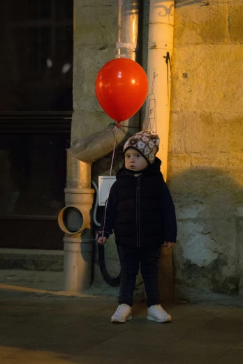 a girl is holding on to a red balloon