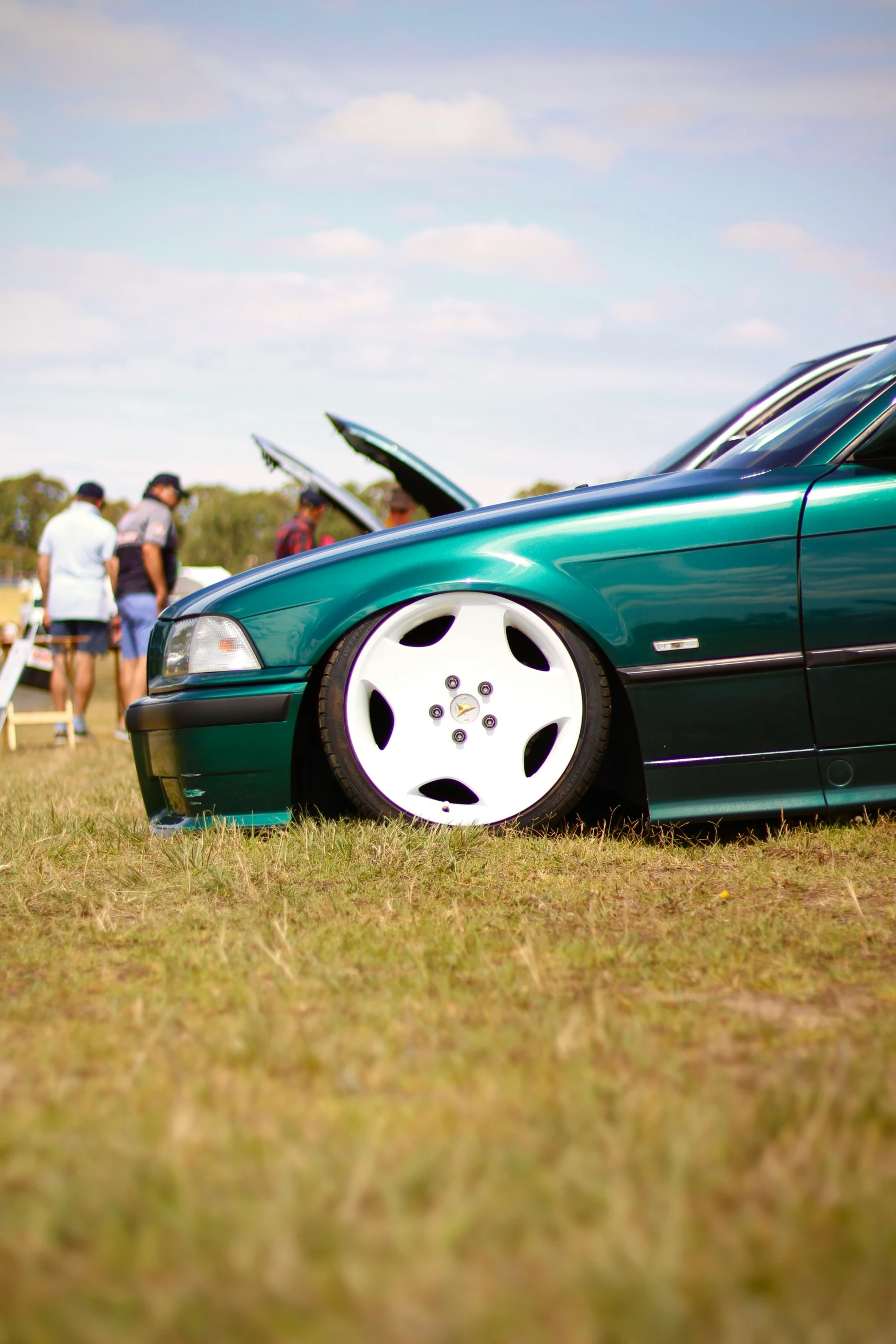 the front wheels on a green car show off the side of it's hood