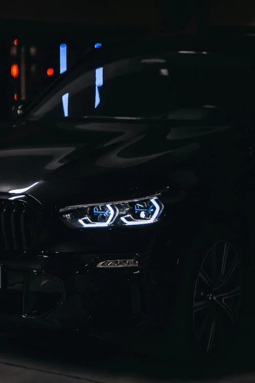 the front end of a black bmw parked in a parking lot at night