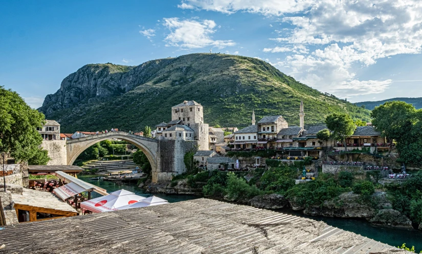 a mountain overlooks buildings, a bridge and a river