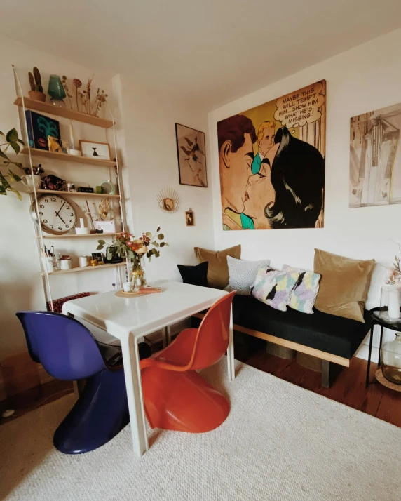 a living room with a white table, colorful chairs, and paintings