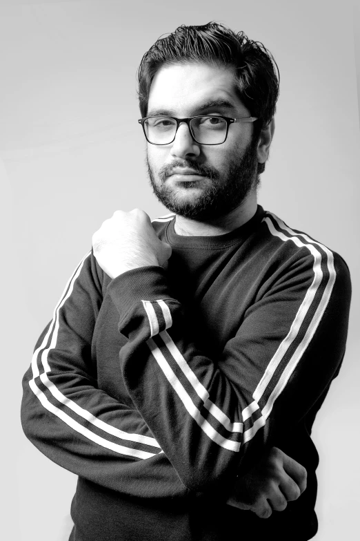 a man is posing in front of a grey wall