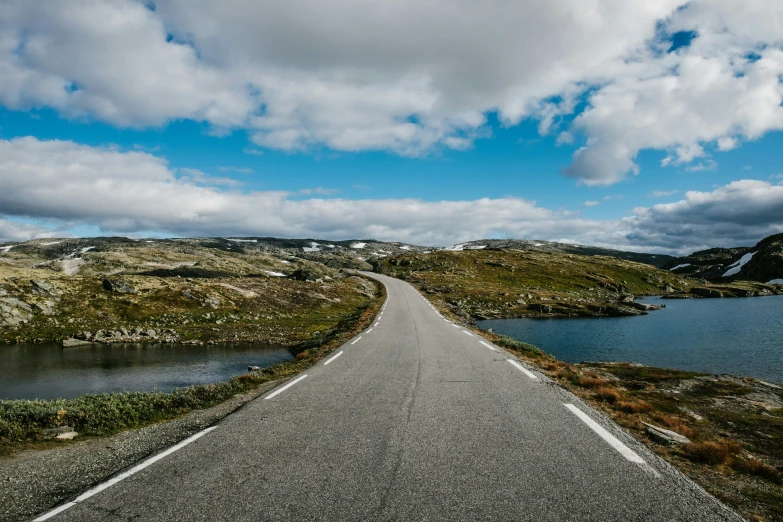 long, straight road going down a winding hillside to a lake