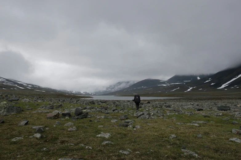 a lone person in the middle of a field surrounded by rocks