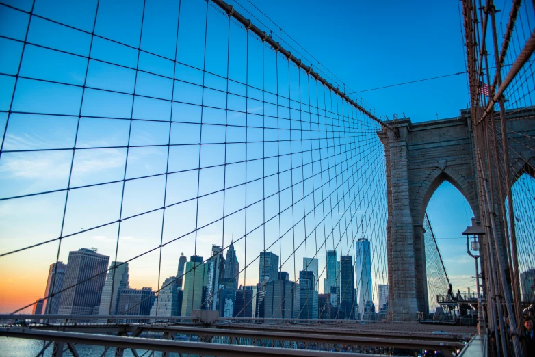 a bridge that has a bunch of cables and buildings behind it