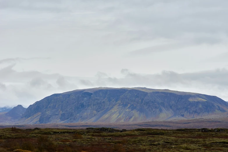 a large mountain rises high over some low terrain