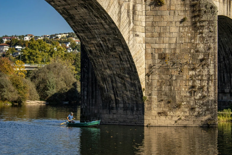 a man in a small boat with a bridge in the background