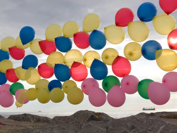 many balloons are floating above a beach