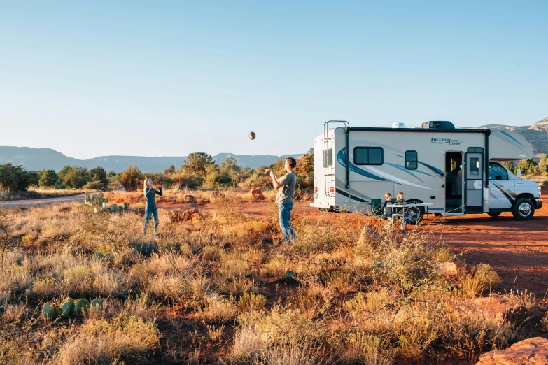 two people looking at a motor home in a field