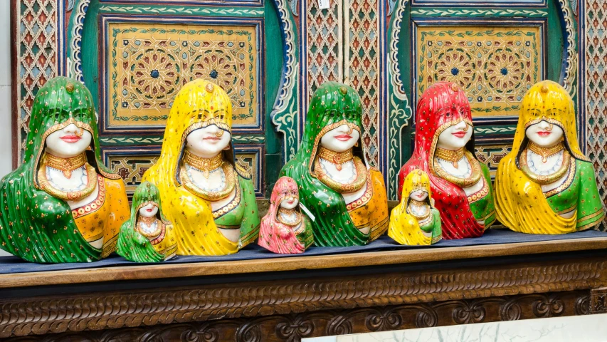 colorfully dressed women sit on display on a wooden table