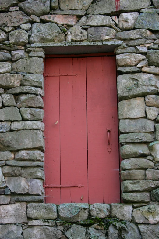 a red door is on a very old stone building