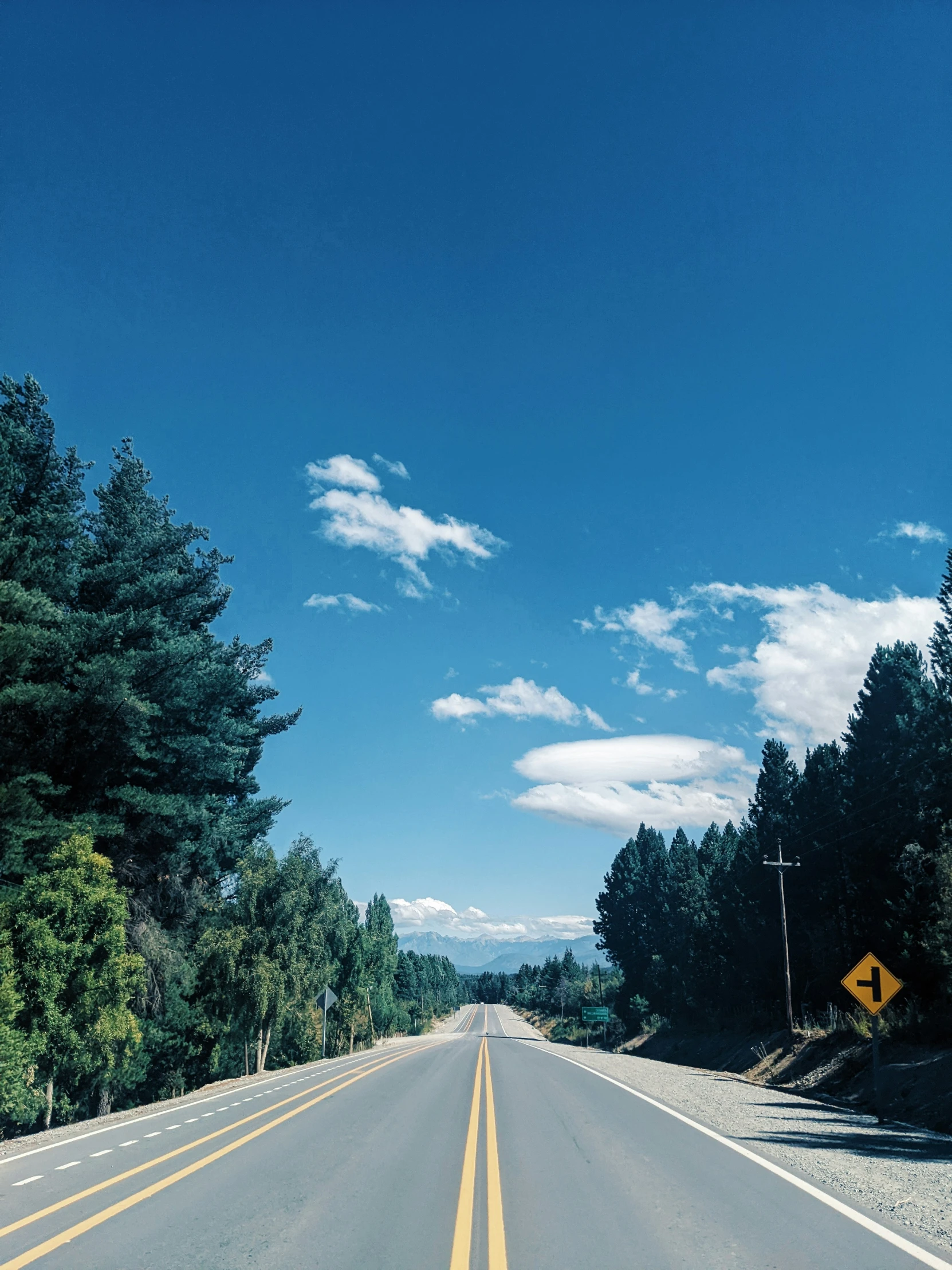 a road under a cloudy blue sky with trees