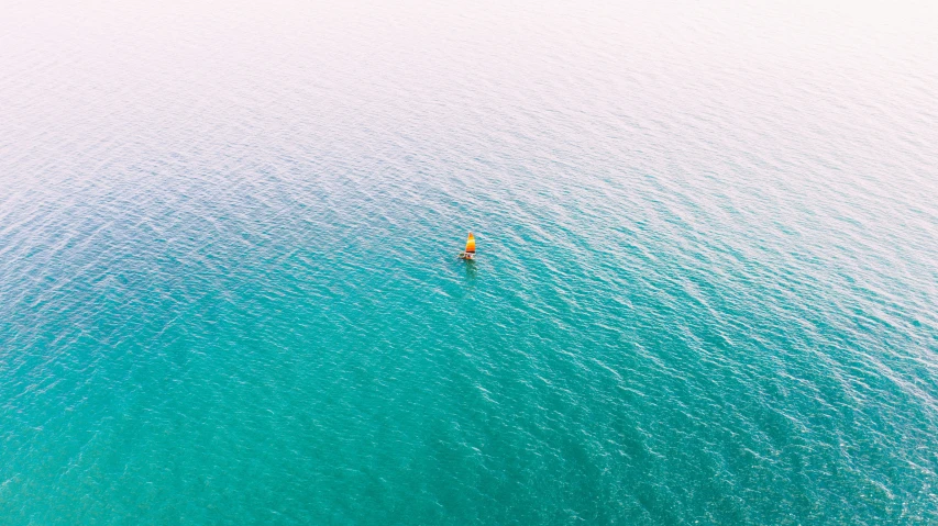 an aerial view of a man in a kayak riding on the ocean