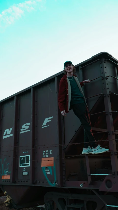 a man standing on top of train cars in the day