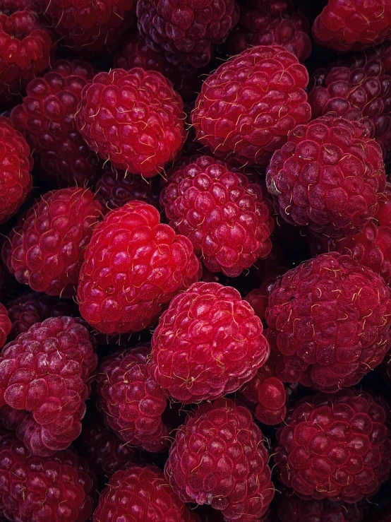 a large pile of red raspberries all piled up together