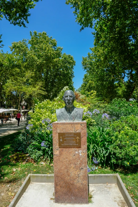 the statue of a man is sitting in front of flowers