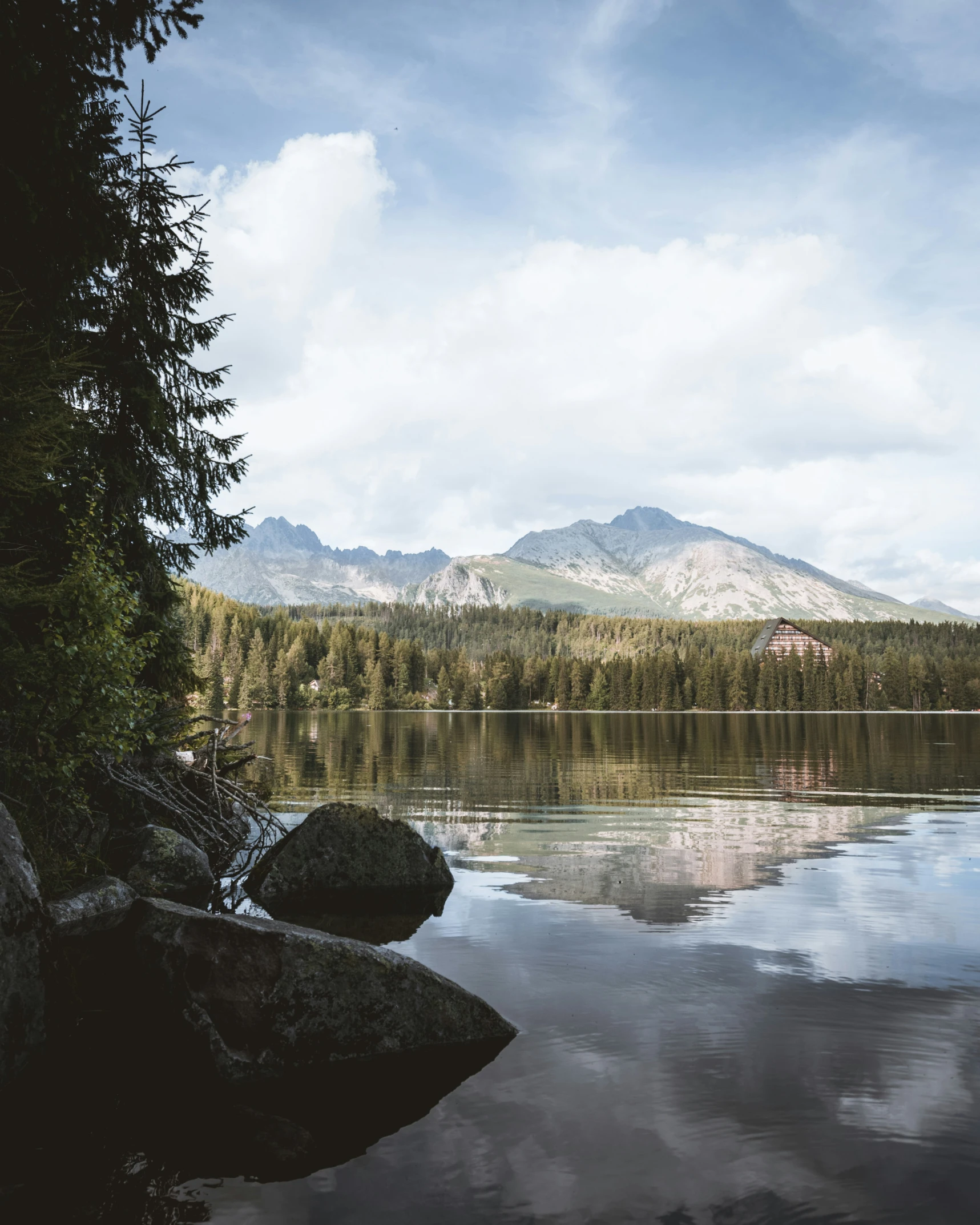 a mountain covered in clouds next to water