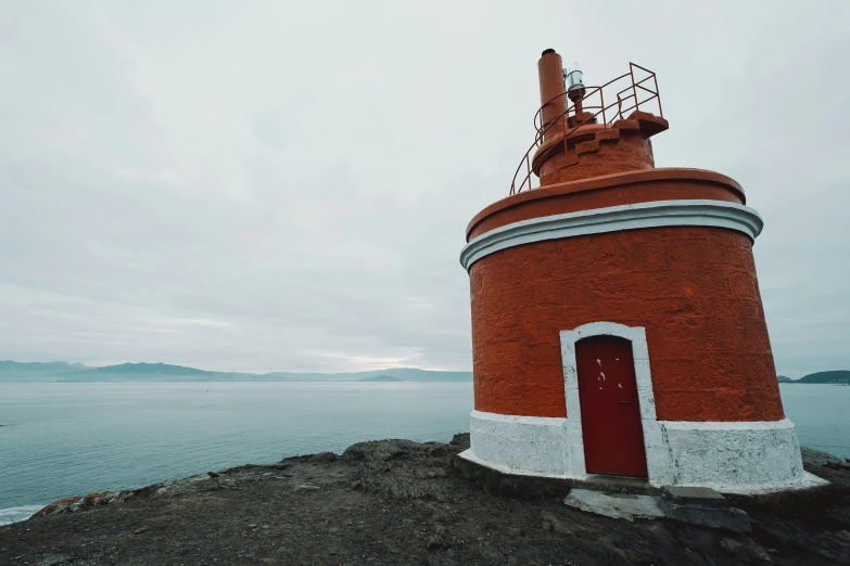 a clock tower stands on the edge of a cliff by the water