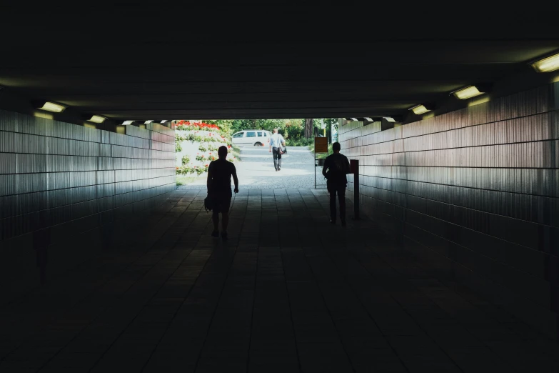 two people walk through a tunnel that contains reflective wallpaper