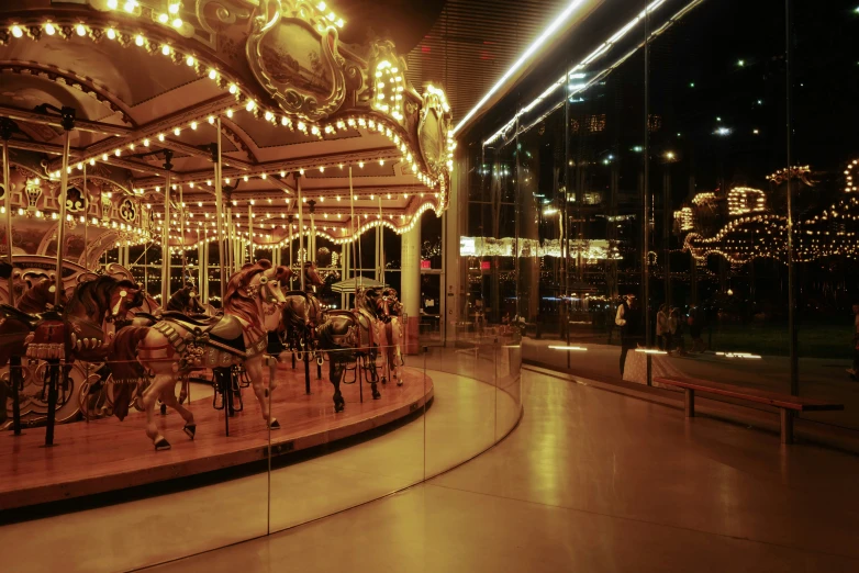 an illuminated carousel with horses and other rides on display