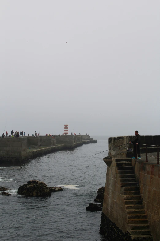 an ocean pier that has people on the pier and a boat in it