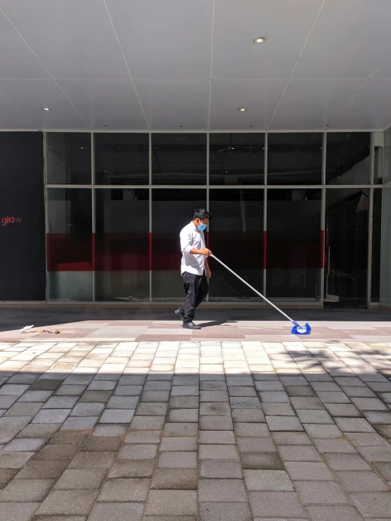 a person mopping the sidewalk outside of a large building